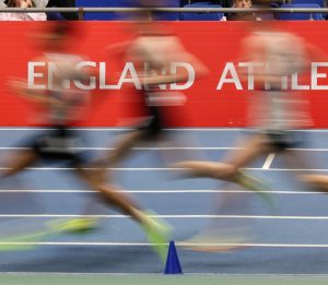 Blurred legs running past England Athletics banner