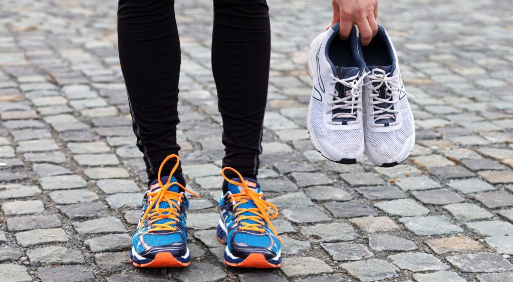 wearing running shoes and holding another pair